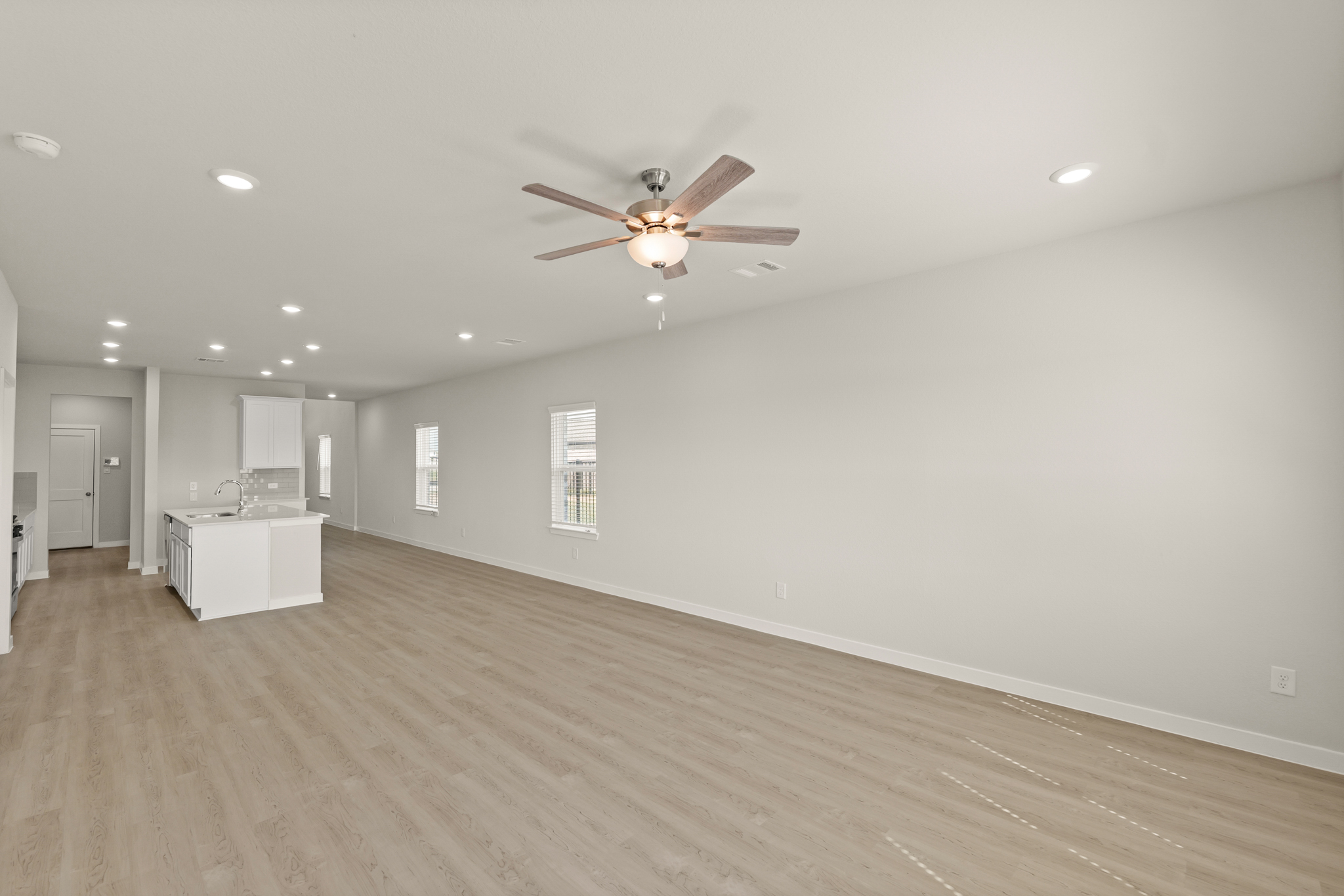 A large empty room with a ceiling fan and a wood floor.