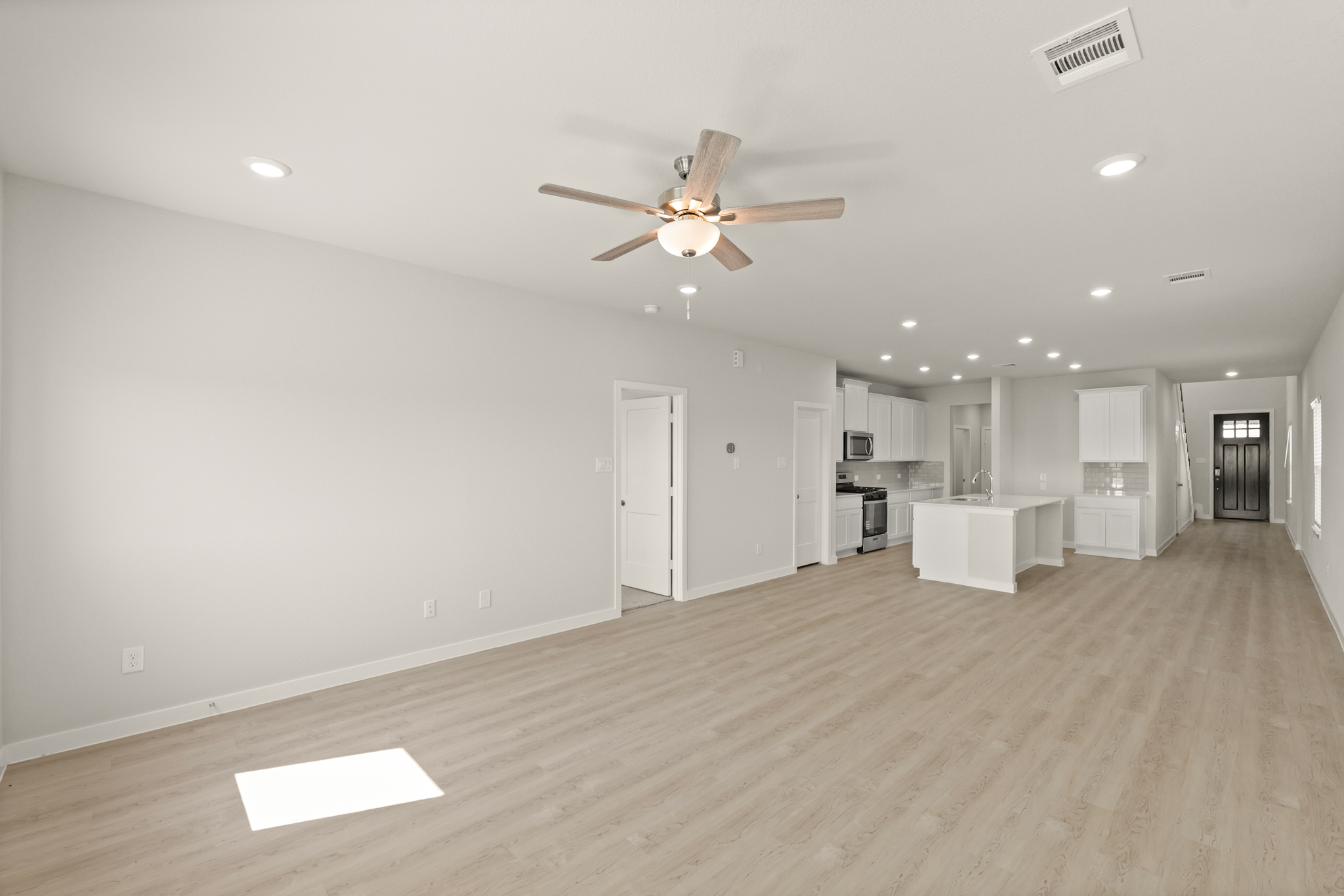 A large empty room with a ceiling fan and a wood floor.
