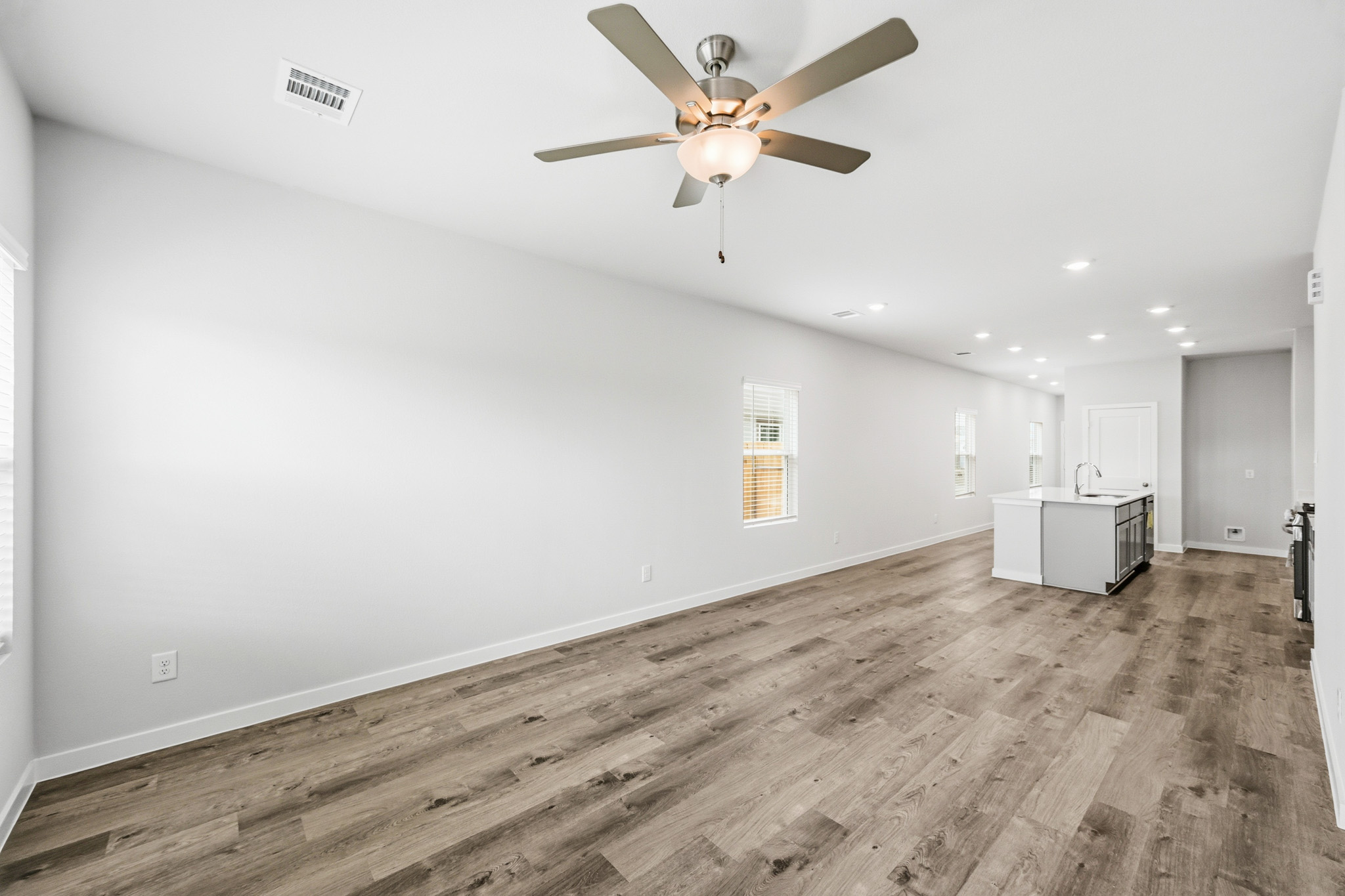 A room with a ceiling fan and wood floor.