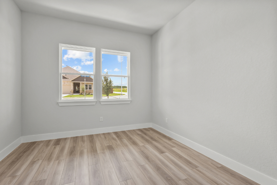 A room with a wood floor and a window with a view of the ocean.