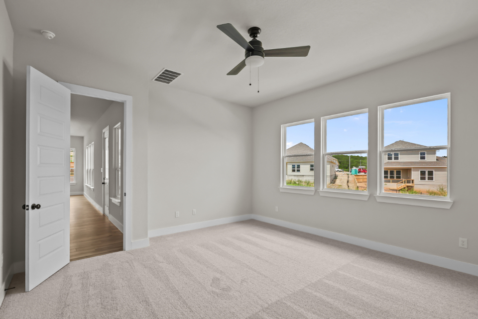A room with a ceiling fan and windows.