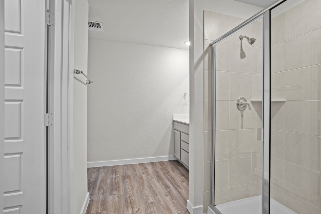 A bathroom with a shower unit and a glass door.