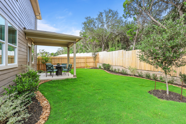 A backyard with a fence and a tree.
