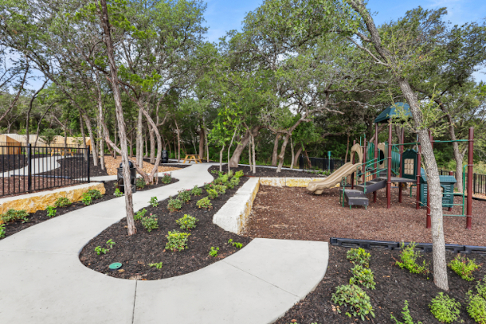 A playground with trees and a slide.