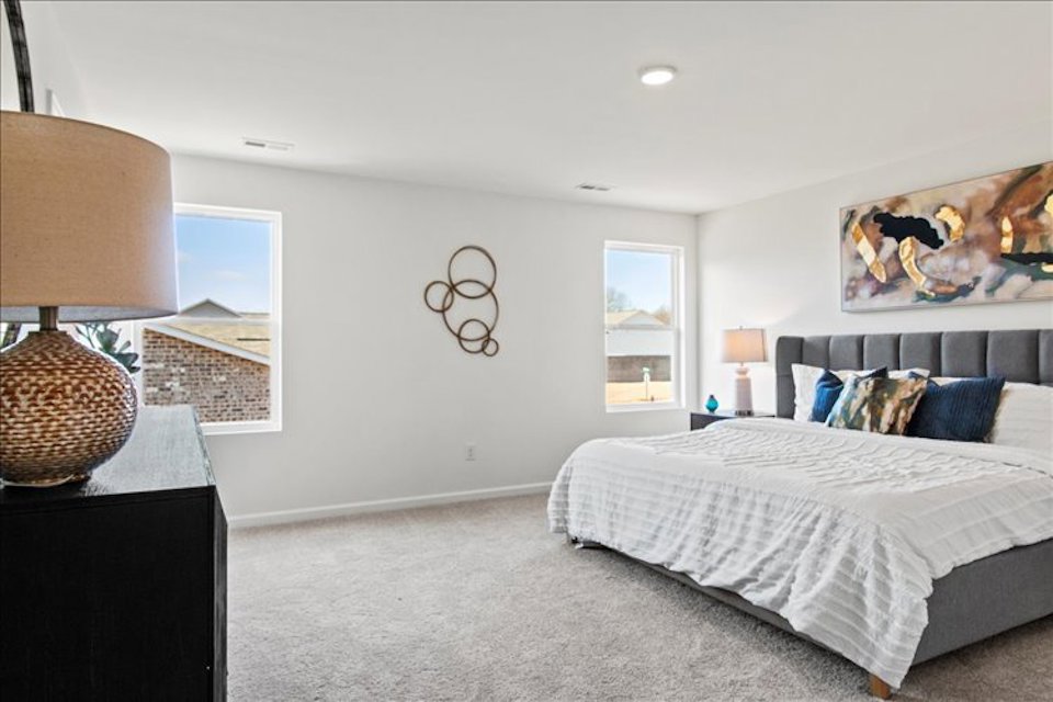 A bedroom with a bed and a lamp.