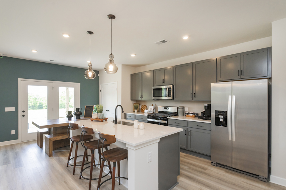 A kitchen with a fridge and stools.