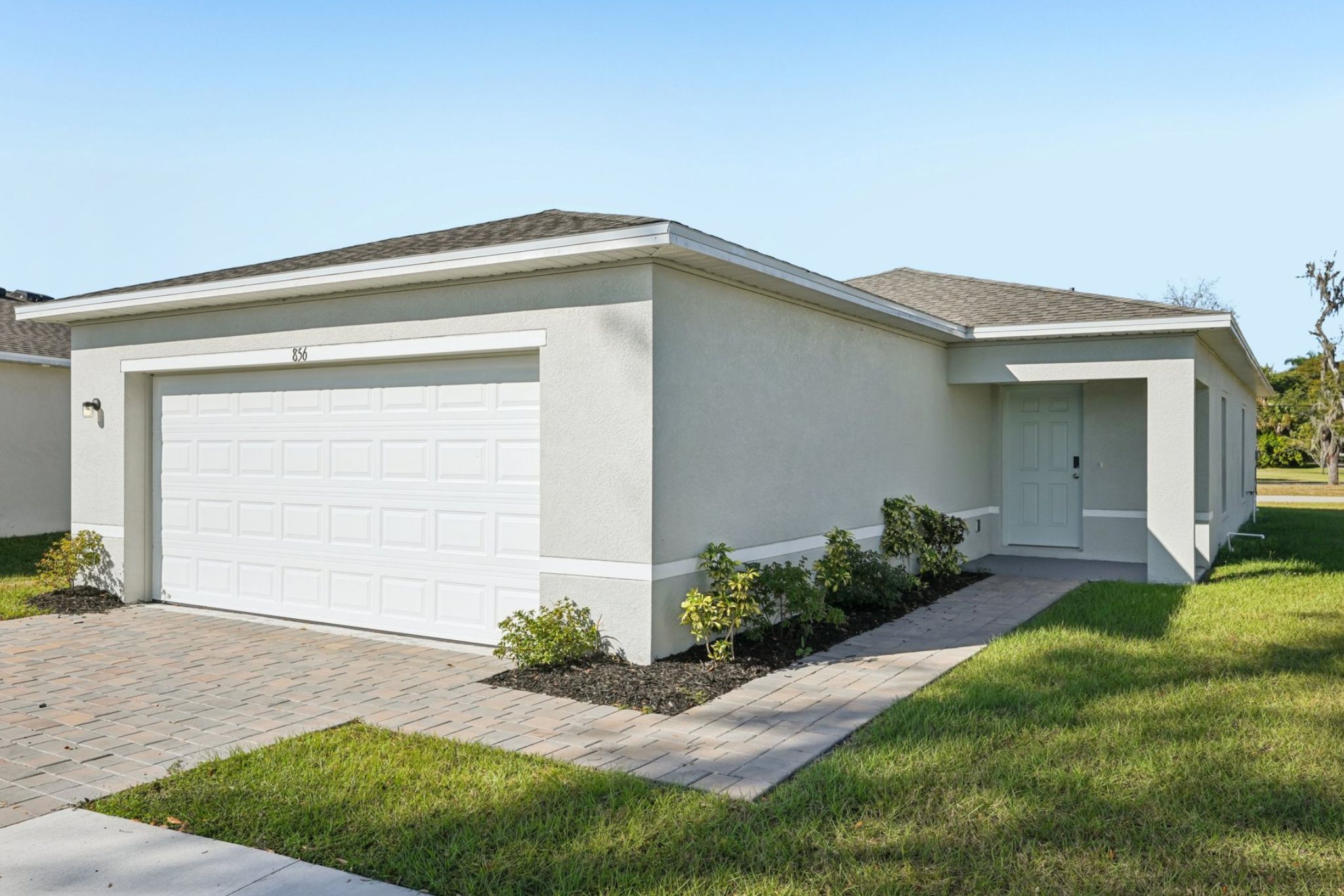 A white garage with a lawn.