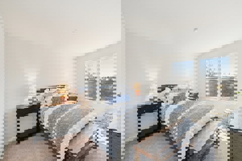 A bedroom with a bed and a bench.